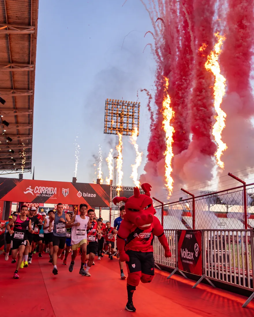 Largada da Corrida do Dragão com fogos e o mascote correndo na frente